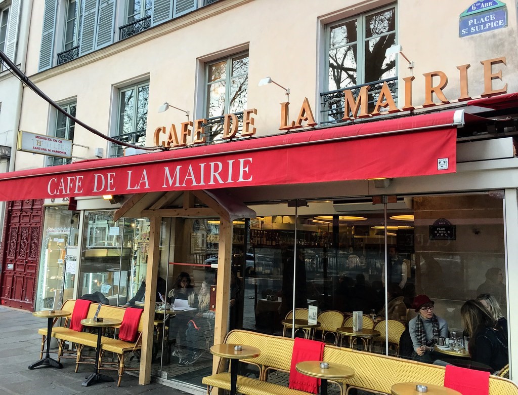 Il Café de la Mairie con la targa vera in alto e quella… falsa all’interno della veranda